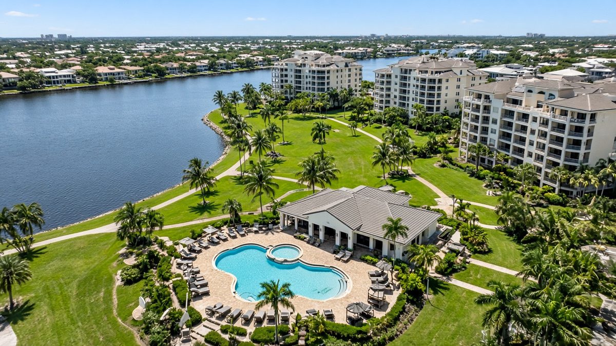 Aerial view of a South Florida condo community with a clubhouse, pool, common lawns and a lake